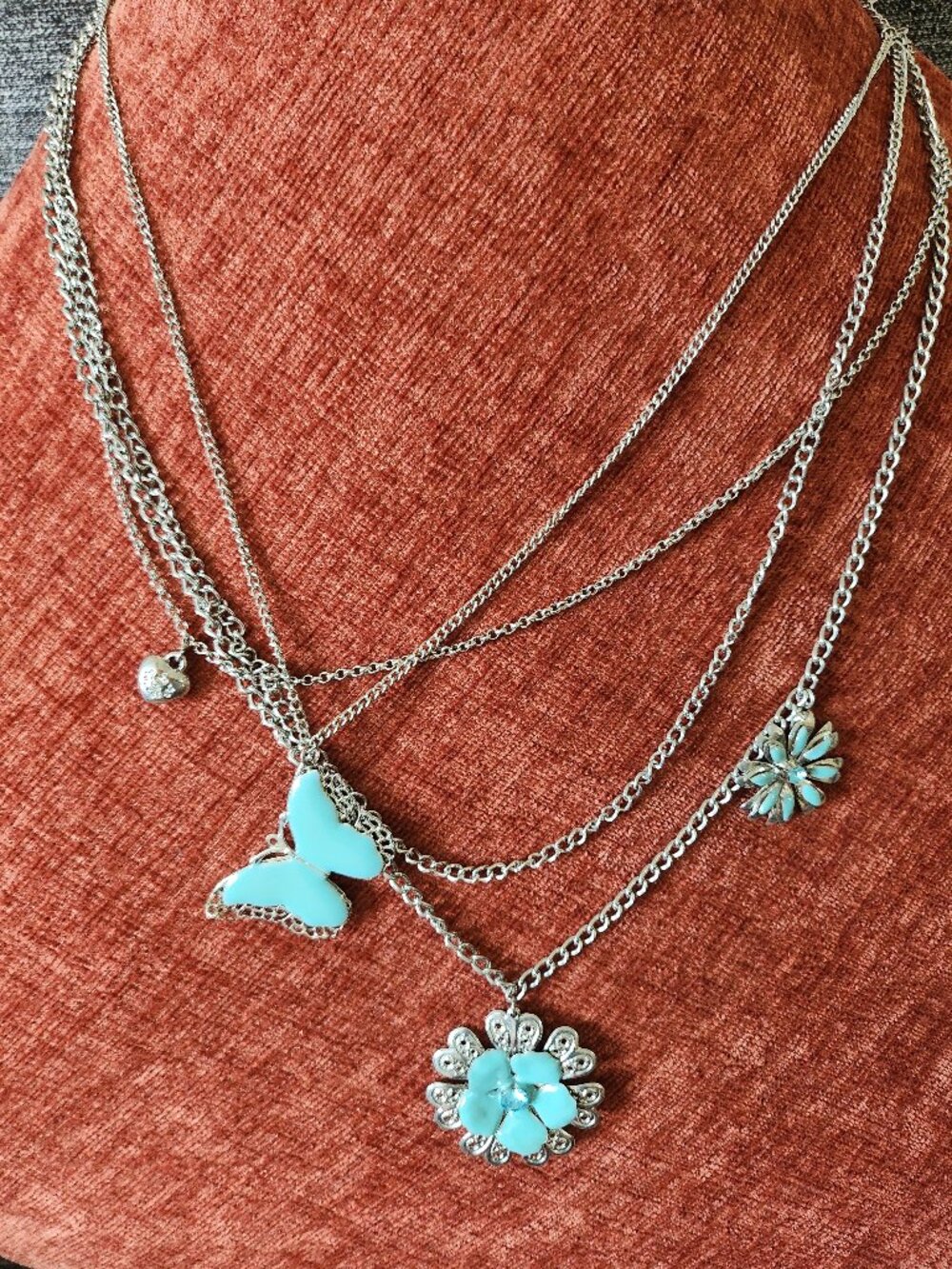Silver layered necklace with butterfly and flower charms in blue accents
